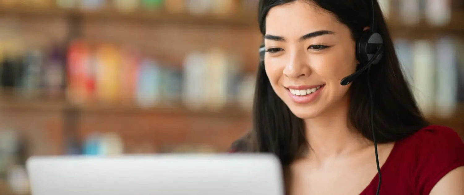 A remote virtual assistant wearing a headset and working at her desk