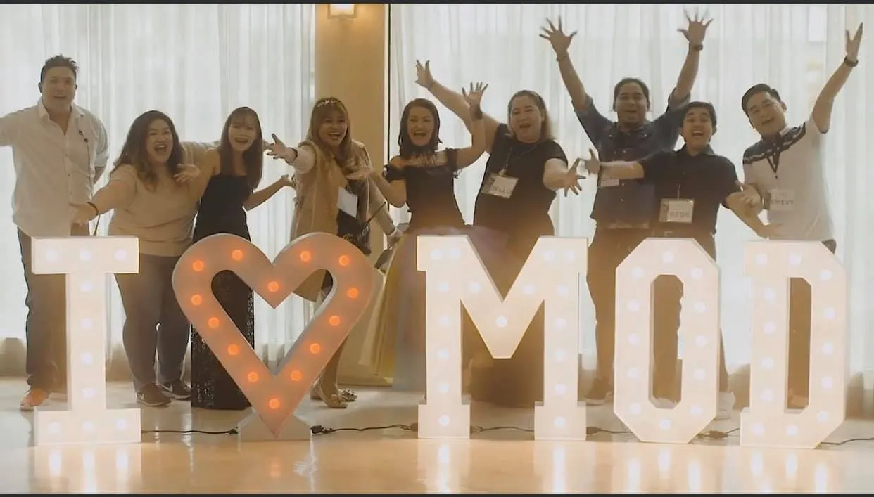 MyOutDesk team members holding a We Love MOD banner